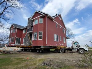 Marcus Building Movers moving a large red house with stone accents on it.